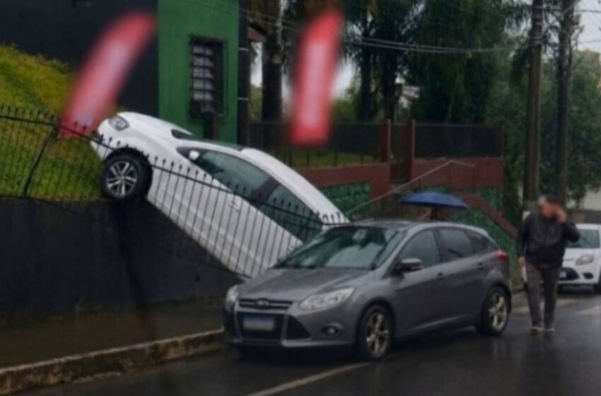  Carro vendido fica pendurado em cerca após acidente em revenda de Caçador